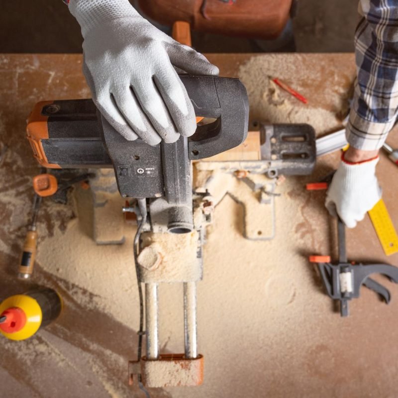 Top view of carpenter holding plank near circular saw in carpentry shop. High quality photo.